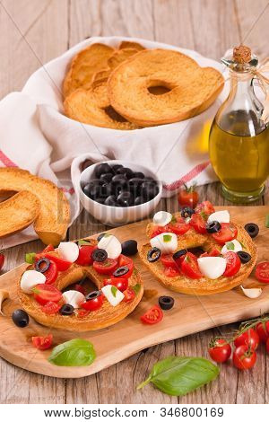 Friselle With Tomatoes And Mozzarella Cheese On Cutting Board.
