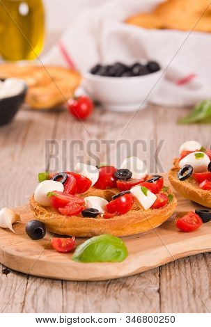 Friselle With Tomatoes And Mozzarella Cheese On Cutting Board.