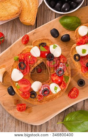 Friselle With Tomatoes And Mozzarella Cheese On Cutting Board.
