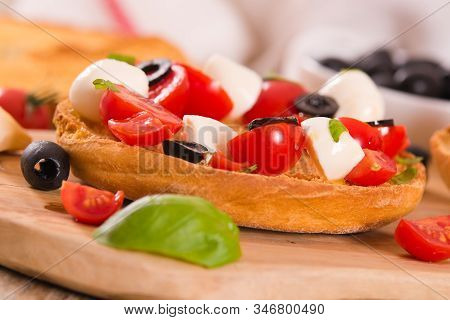 Friselle With Tomatoes And Mozzarella Cheese On Cutting Board.