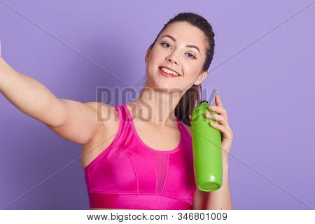 Portrait Of Energetic Beautiful Positive Female Making Selfie Isolated Over Lilac Background, Wearin