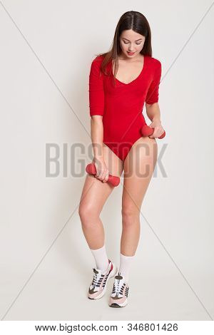 Full Length Picture Of Cute Beautiful Fitness Trainer Wearing Red Sport Combidress, White Socks And 