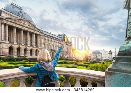 Woman Tourist In Casual Clothes Stands With Her Back To The Camera And Waving The Flag Of Belgium Ag