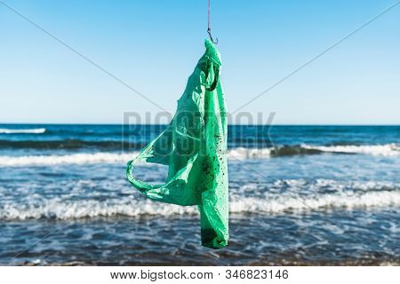 closeup of a used green plastic bag in a fish hook, freshly fished in the ocean