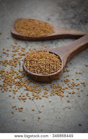 Fenugreek Seeds In Wooden Spoon On Textured Background