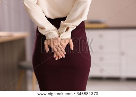 Young Woman Suffering From Hemorrhoid In Office, Closeup