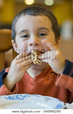 Happy Little Boy Eats Pancakes Hands. Portrait Of Small Cute Little Boy Child Caucasian Sitting By T