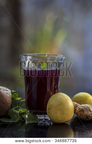 Beetroot Juice With Some Mint Leaves Lemon Juice And Ginger In It On Black Glossy Surface In A Glass