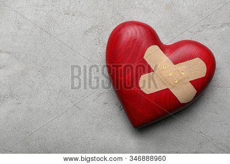 Red Wooden Heart With Sticking Plasters On Light Grey Stone Table, Top View. Space For Text