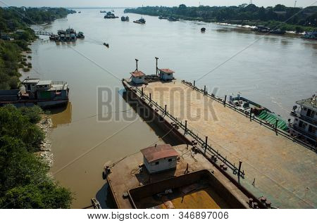 Old rusty ships on brown water of Pazundaung Greek. Yangon, Myanmar