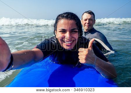 Latina-merican Beautiful Girl Surfer Instructor Making Selfie Photo Wirh Friend Thumbs Up On Camera 
