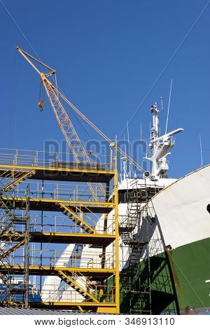 Ship in the shipyard for maintenance and repair work with scaffolds and crane.