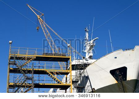 Ship In The Shipyard For Maintenance And Repair Work With Scaffolds And Crane.