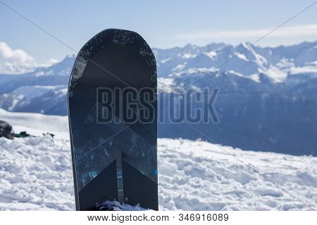 Snowboard Stands On The Background Of The Snowy Mountains Of The Caucasus, The Ski Resort Rosa Khuto