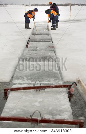 Workers Rafting Ice Blocks Along A Channel Cut Out By A Frozen Lake