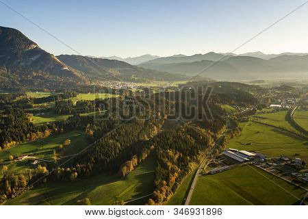 Aerial View Of Green Meadows With Villages And Forest In Austrian Alps Mountains.