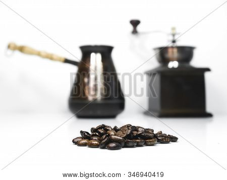 Close-up To Coffee Beans And A Wooden Coffee Grinder With A Cezva On The Background