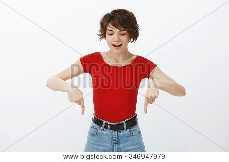 Excited Good-looking European Female Short Pixie Haircut Look Pointing Down Amazed Entertained Curio
