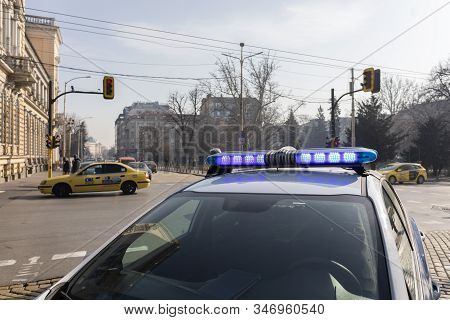 A Police Officer Standing Near His Car With The Light On. Police Stand Guard At A Roadblock, Police 