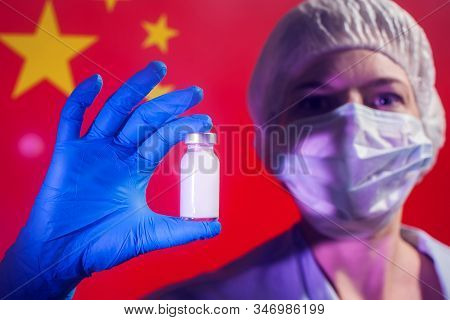A Doctor In Blue Medical Gloves And Mask Holding An Ampula With Vaccine In Front Of Flag Of China. C
