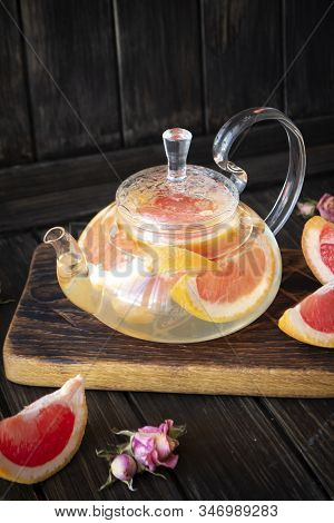 Glass Teapot With Grapefruit Tea On Dark Rustic Background