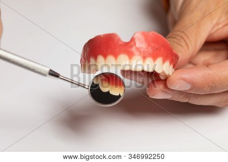 Denture Prosthesis In Doctor Dentist Hands, Checking With Mirror