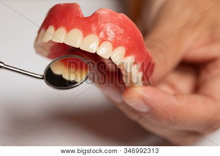 Denture Prosthesis In Doctor Dentist Hands, Checking With Mirror