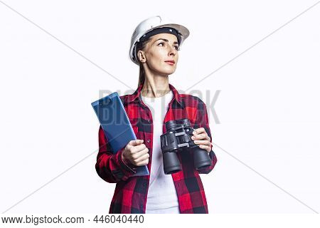 Young Woman In Construction Clothes With A Clipboard And Binoculars On A Light Background.
