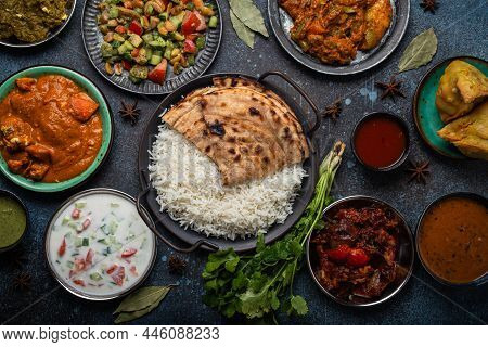 Assorted Indian Ethnic Food Buffet On Rustic Concrete Table From Above: Curry, Fried Samosa, Rice Bi
