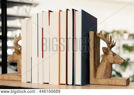 Wooden Deer Shaped Bookends With Books On Shelf Indoors