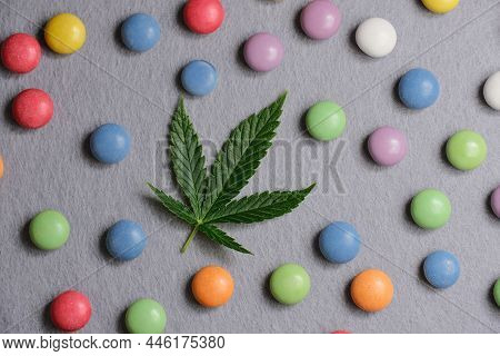 Cannabis Leaf With Colorful Candy Confetti Close Up. Marijuana Sweets With Cbd And Thc On Gray 
Back
