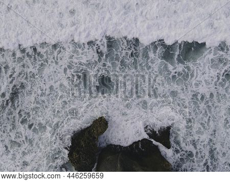 Top Down Aerial View Of Giant Ocean Waves Crashing And Foaming In Coral Beach
