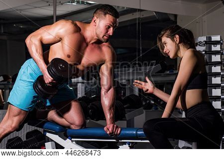 Athlete Doing Exercise With Dumbbell At The Gym. Woman Trainer With Muscular Man Doing Functional Tr