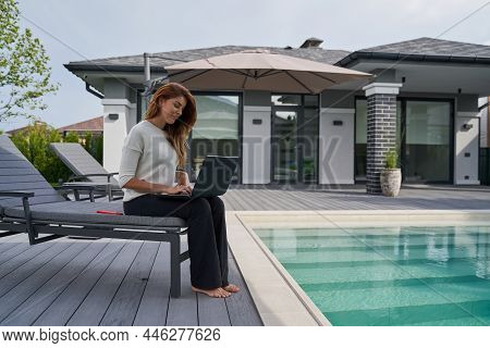 Full Length View Of The Cheerful Pretty Lady Using Laptop To Chat With Friend Online Or Working At T