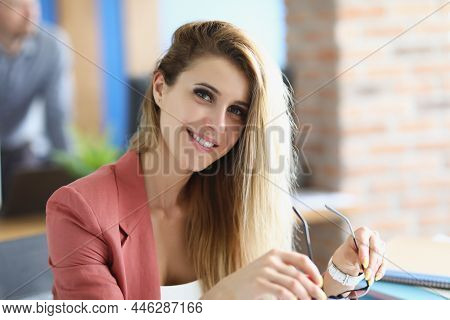 Portrait Of Attractive Blonde Lady Sit In Personal Cabinet Holding Glasses. Smiling Employee In Styl