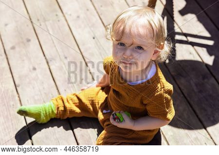 High Angle View Of A Mischievous Three Year Old Toddler Sitting On Wooden Decking Holding Lighters W