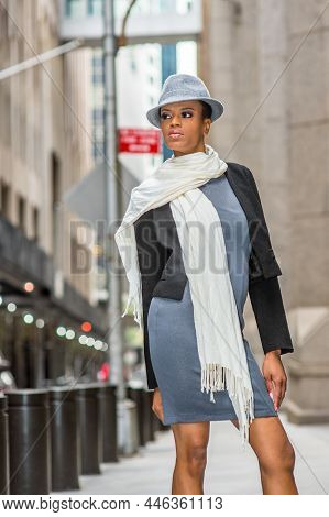 Dressing In A Black Woolen Cropped Jacket,  A Gray Fitted Dress, A Long White Scarf Around Her Neck,