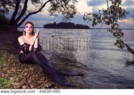 Sensual Mermaid Posing Near Seashore On Rocks While Wearing Artistic Makeup And Facial Strassses And