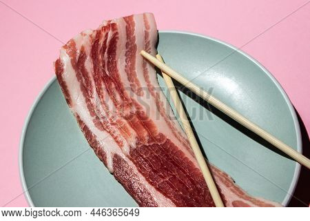 Bacon On A Pink Background. Raw Bacon On A Plate. Chinese Sticks Next To Pieces Of Meat. Pork Meat
