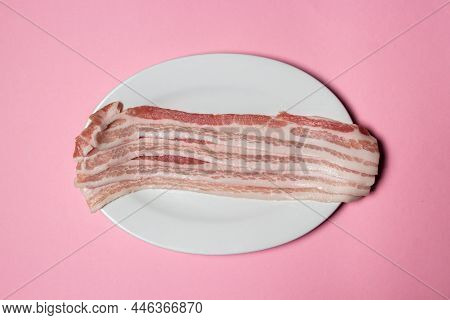 Bacon On A Pink Background. Raw Bacon On A Plate. Fresh Slices Of Pork Meat