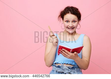 Attractive Woman Writing In A Red Notebook With A Pen Study Pink Color Background Unaltered