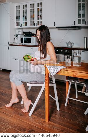 Pregnant Eating Healthy Food. Pregnant Woman In The Kitchen. Pregnant Eats Green Salad. Pregnant On