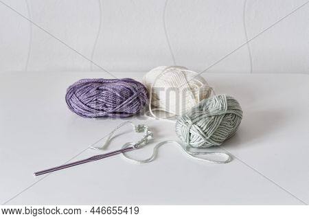 Crochet Hook, Chain Of Loops Made Of Light Green Threads Over Background Of Skeins Of Acrylic Yarn O