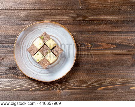 Indian Sweets Lying On A Brown Plate On A Brown Wooden Background. Assorted Indian Sweets: Coconut S