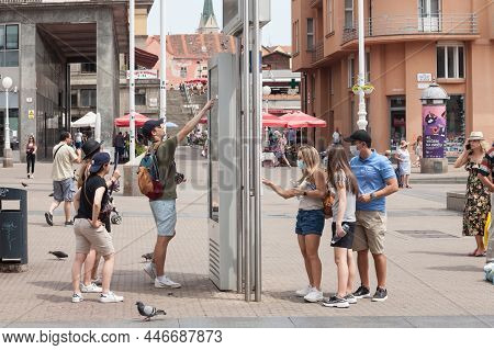 Zagreb, Croatia - June 20, 2021: Group Of Young Tourists Looking At A Map, Trying To Orientate Thems