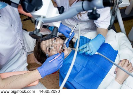 Dentist With Assistant Under Microscope Treats The Patient's Teeth. Modern Progressive Dentistry