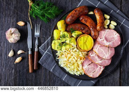 Schlachtplatte, Fried Bratwurst, Smoked Pork Neck, Boiled Potatoes, Sauerkraut And Mustard On A Blac