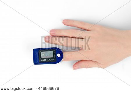 Pulse Oximeter On The Finger Of A Female Hand, White Background. Pulse Oximeter Shows Saturation 99