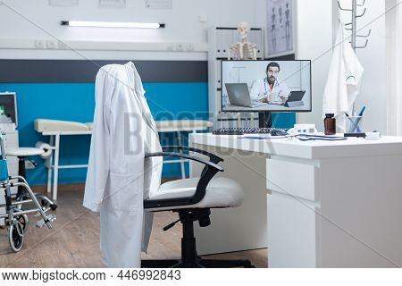 Empty Medical Office Room With Remote Doctor Having Online Videocall Meeting Conference On Computer 