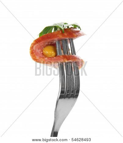 Piece of sausage with greens and mustard on fork